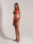 Confident red bikini model showcasing sleek silhouette against neutral backdrop