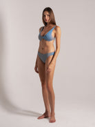 Modern blue textured bikini worn by a tall female model, studio-shot.