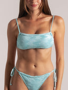 Close-up of woman wearing aqua textured bandeau bikini top with thin straps and matching tie-side bottom