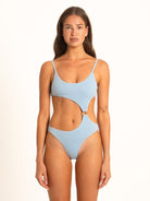 Model in light blue textured one-piece swimsuit with ring cutout design, front-facing pose