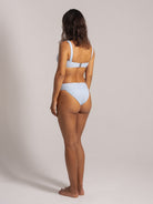 Back view of woman wearing a light blue ribbed bikini with wide shoulder straps and high-waisted cheeky bottoms