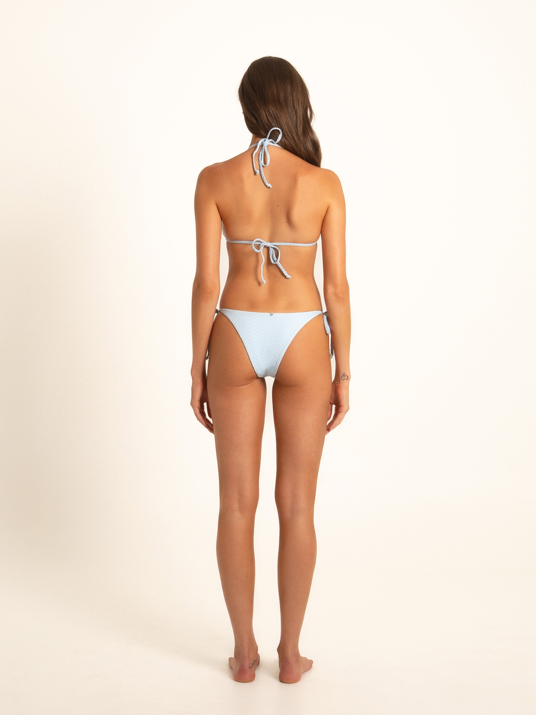 Rear view of model in high-cut light blue bikini with adjustable ties