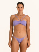 Front view of woman wearing purple bandeau bikini top with cross shoulder straps.