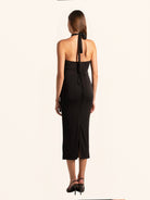 Back view of black cut out midi dress with halter strap and open back