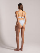 Back view of a model wearing a blue ribbed bikini set with adjustable straps and mid-rise bottoms.