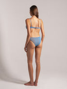 Back view of woman wearing a light blue ribbed bikini with adjustable shoulder straps and clasp closure