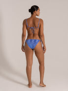 Side-back angle of blue patterned bikini featuring tie-side bottoms and thin adjustable shoulder straps.