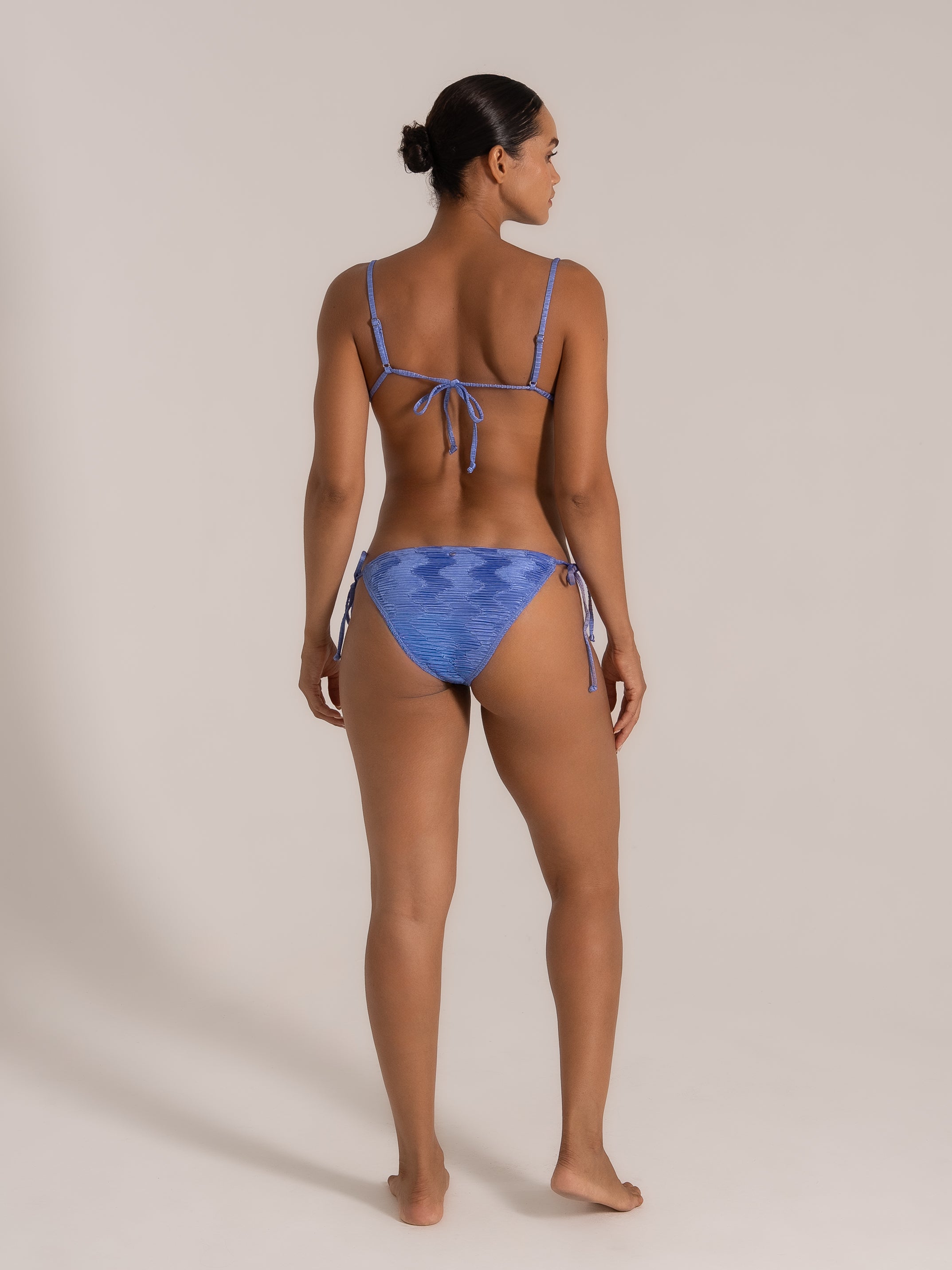 Side-back angle of blue patterned bikini featuring tie-side bottoms and thin adjustable shoulder straps.