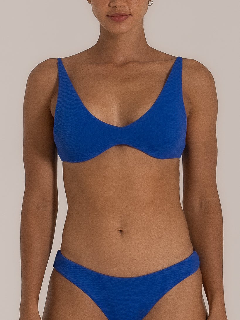 Front view of a woman wearing a vibrant blue V-neck bikini set with a textured finish and a flattering high-leg bottom, offering a supportive and stylish swimwear look.