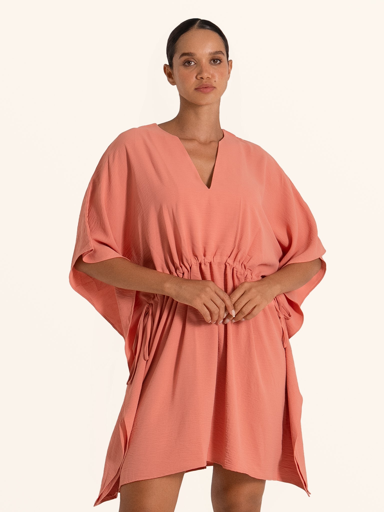 Front view of coral pink loose mini dress with V neckline and elastic waist