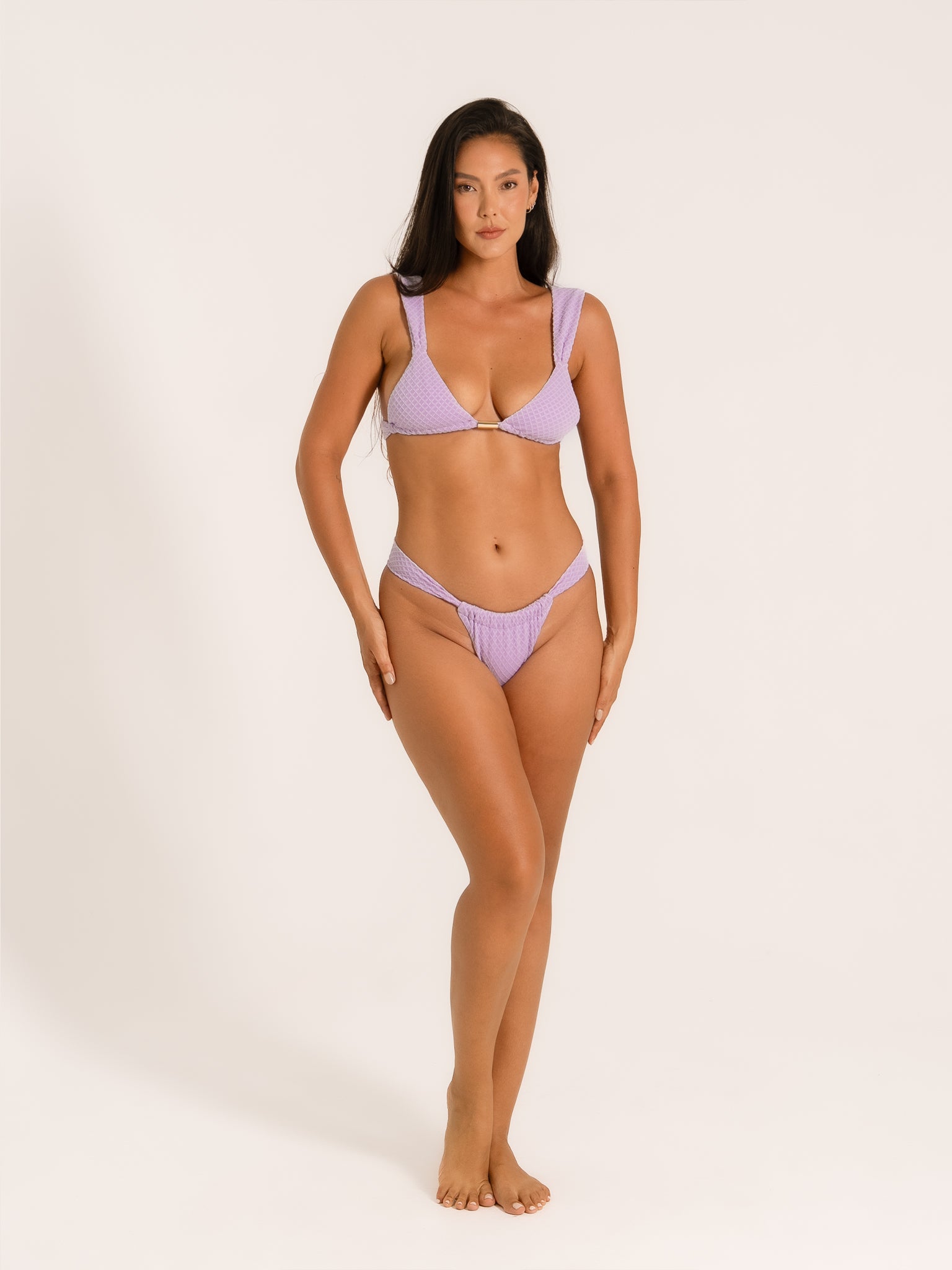 Full body view of woman wearing lilac textured V-cut bikini bottom with high leg style.