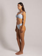 Side view of woman wearing a light blue ribbed bikini with wide shoulder straps and high-waisted bottoms