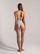 Rear angle of a light blue textured bikini featuring a clasp-back top and high-cut bottom design.