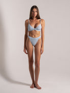 Full body view of model wearing light blue ribbed bikini set with high leg bottom and bra-style top