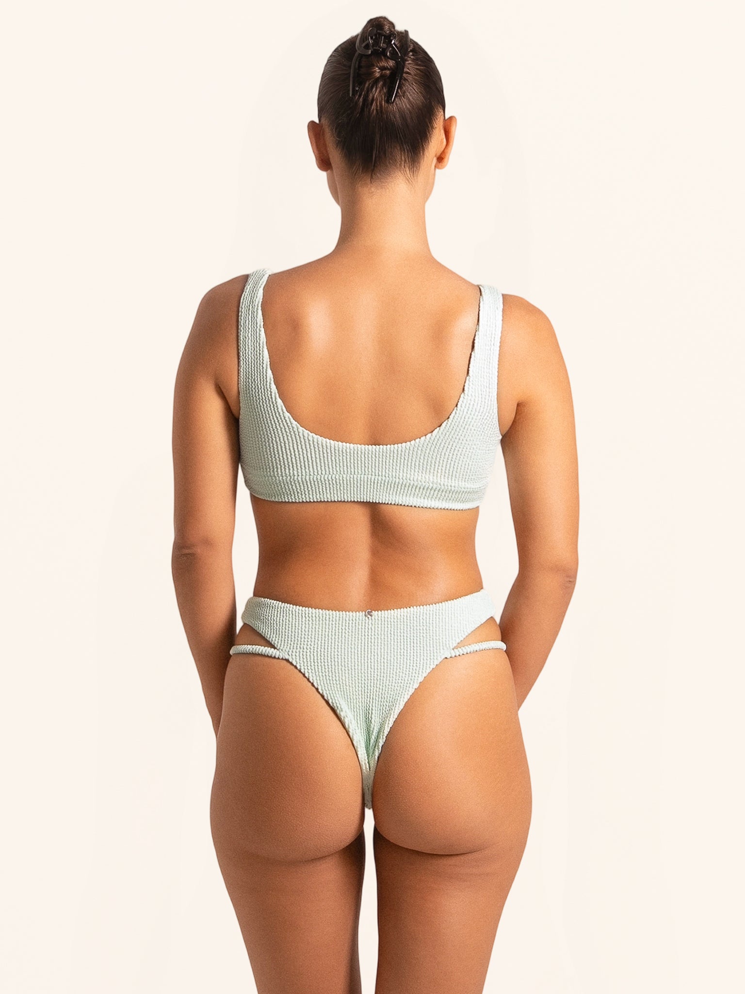 Light green bikini bottom in textured fabric with cut-out waist and high-leg cut.