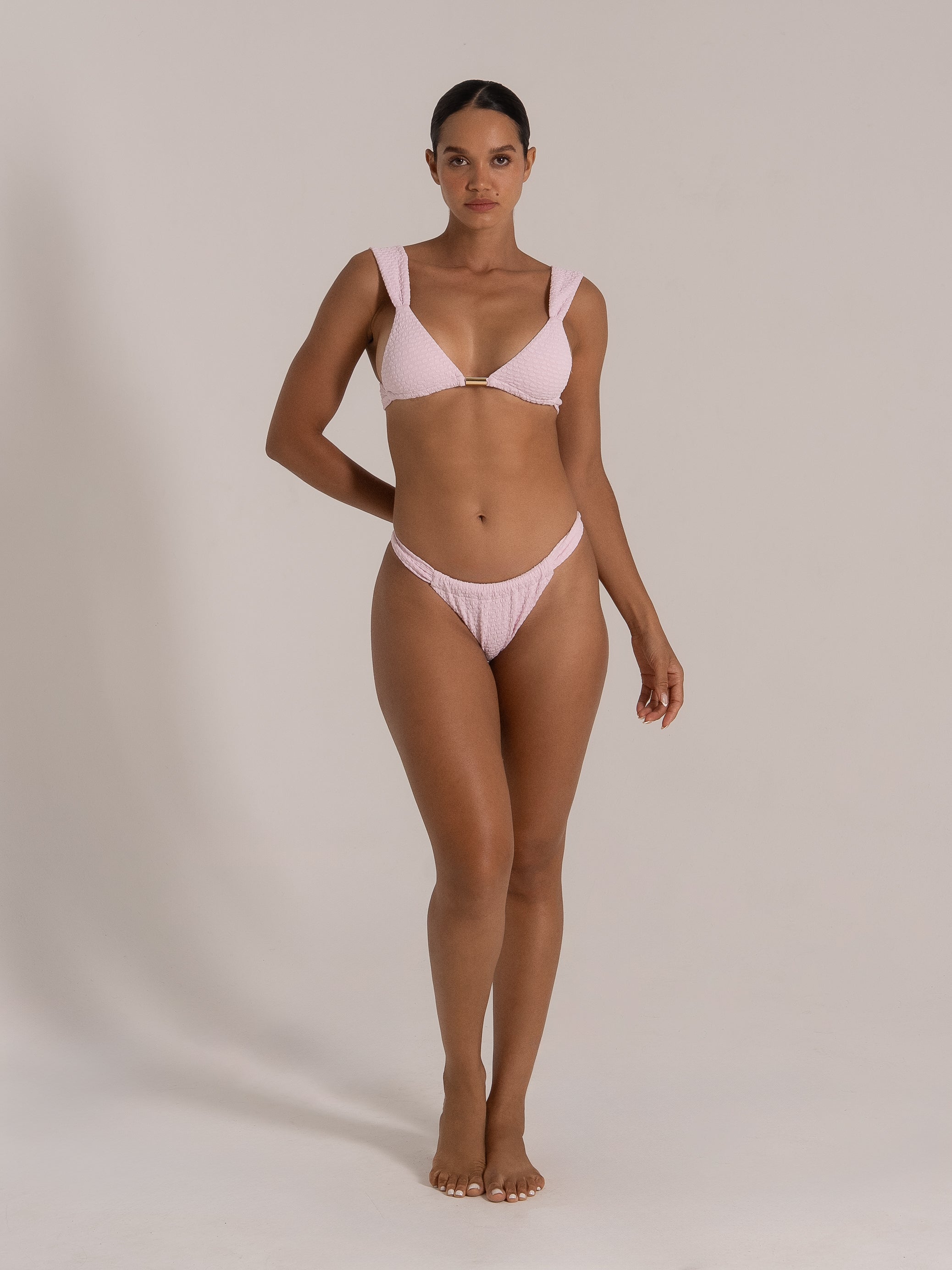 Front view of a light pink textured bikini set with deep V neckline and metal bar detail.