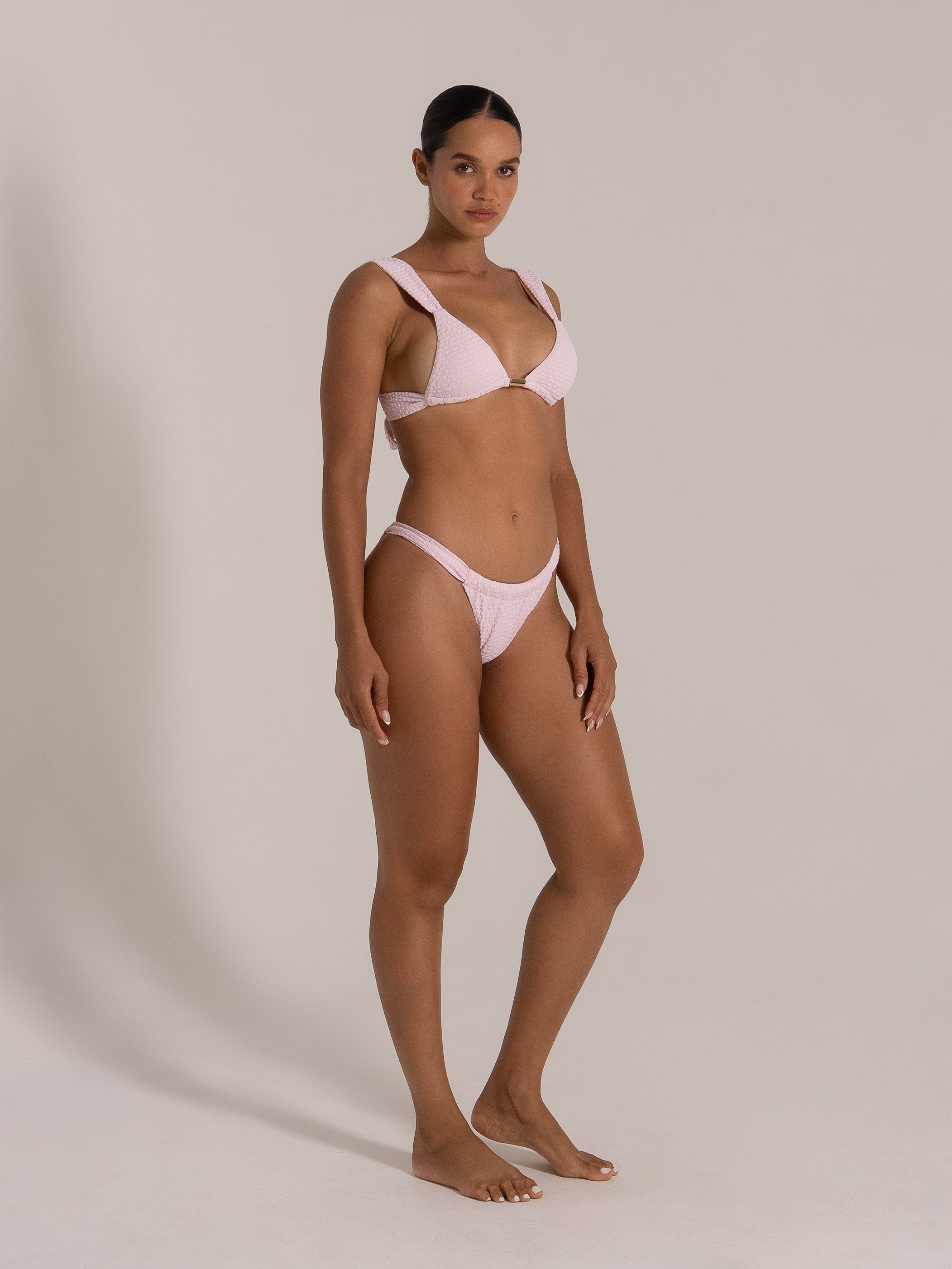 Angled front view of a light pink bikini set with wide straps and V-shaped neckline with metallic accent.