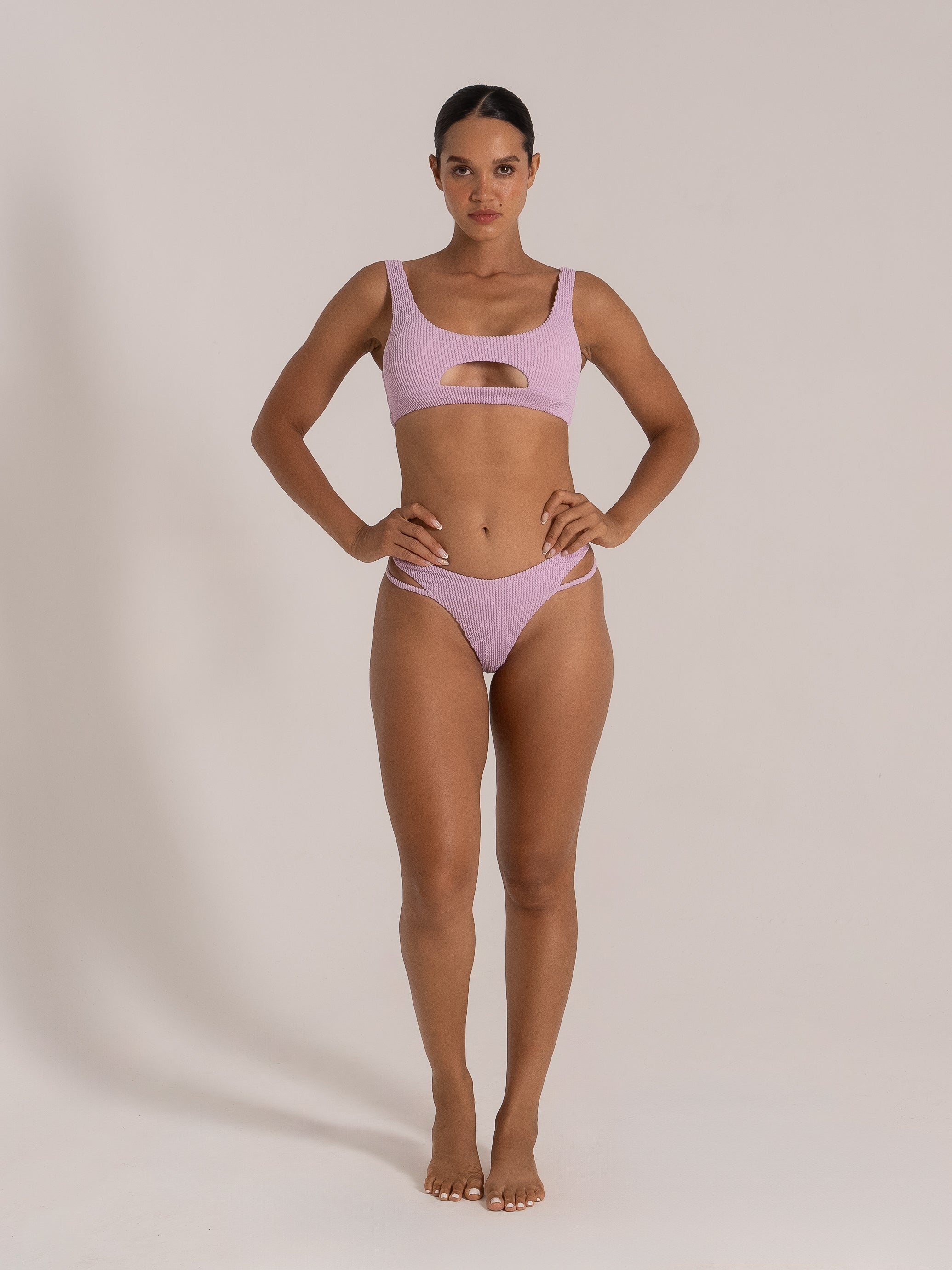 Model wearing lilac textured bikini with keyhole cut-out top and strappy bottom front view