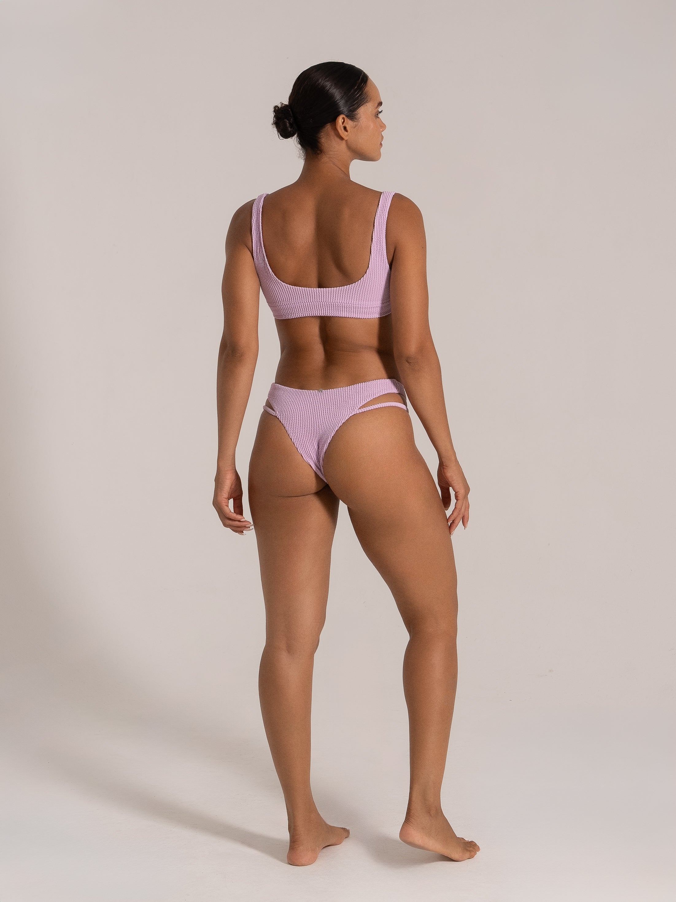 Back view of model wearing lilac bikini with scoop back and cheeky cut bottom