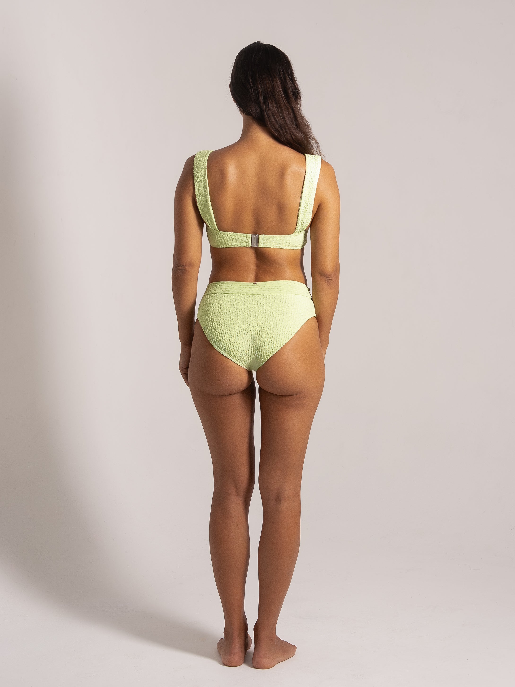 Back view of a lime green textured bikini with wide shoulder straps and clasp closure.