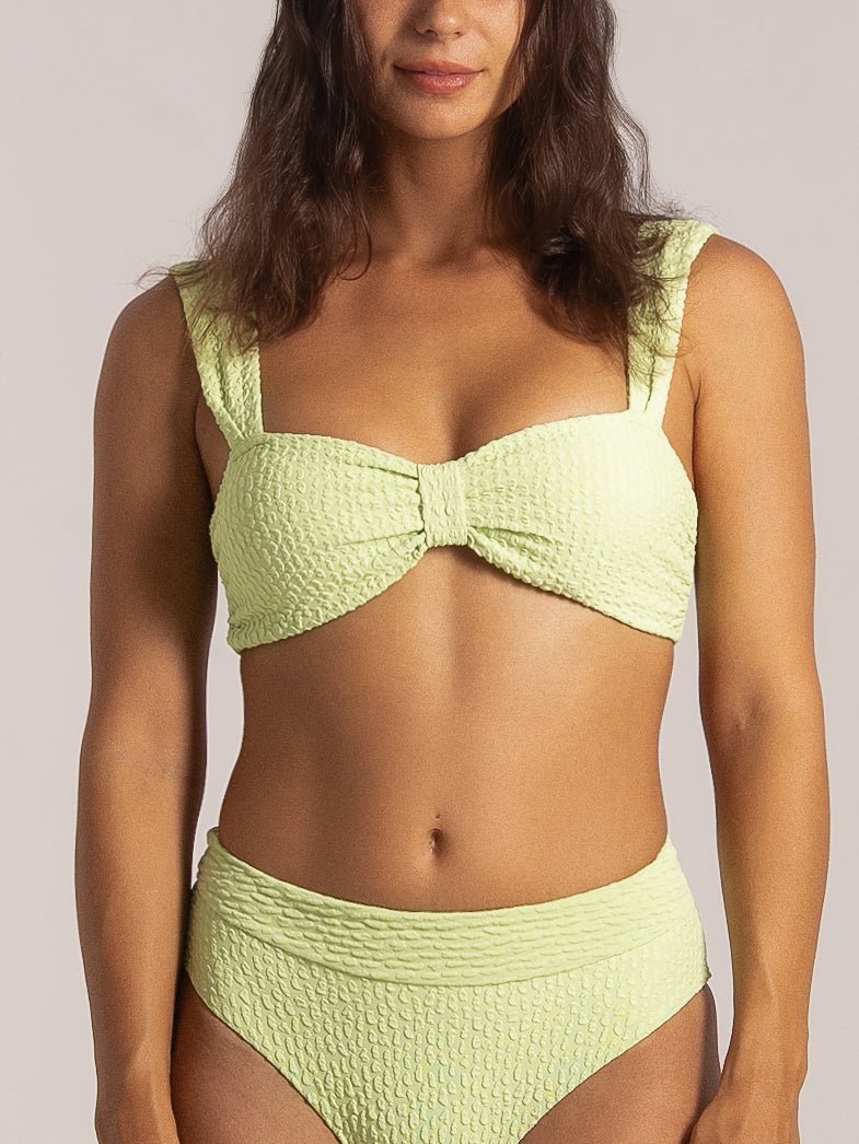 Front close-up of a lime green bikini featuring wide straps and a center knot on the top.