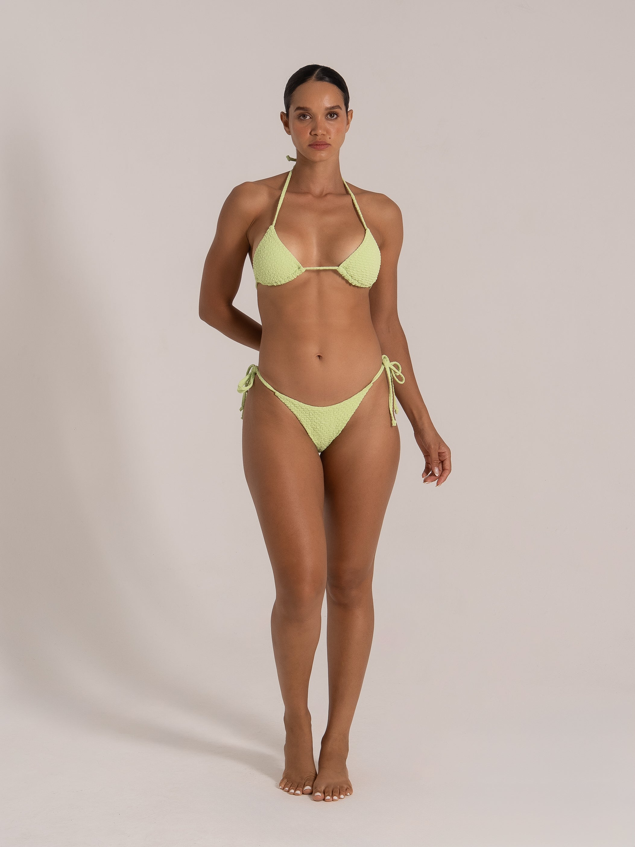 Front view of lime green textured triangle bikini with halter tie and minimal coverage bottom.
