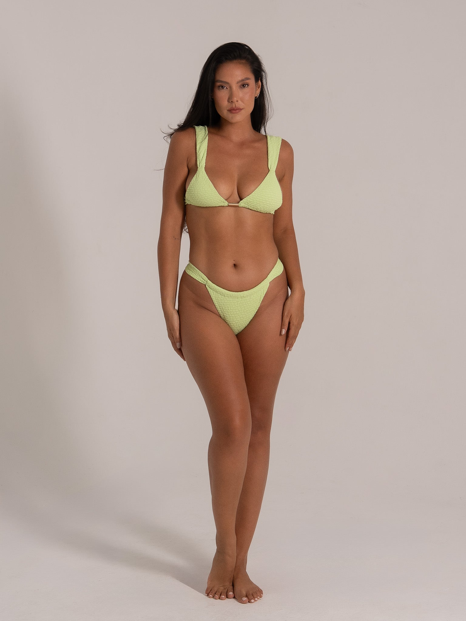 Front view of woman in V-neck lime green bikini with thick straps and textured finish