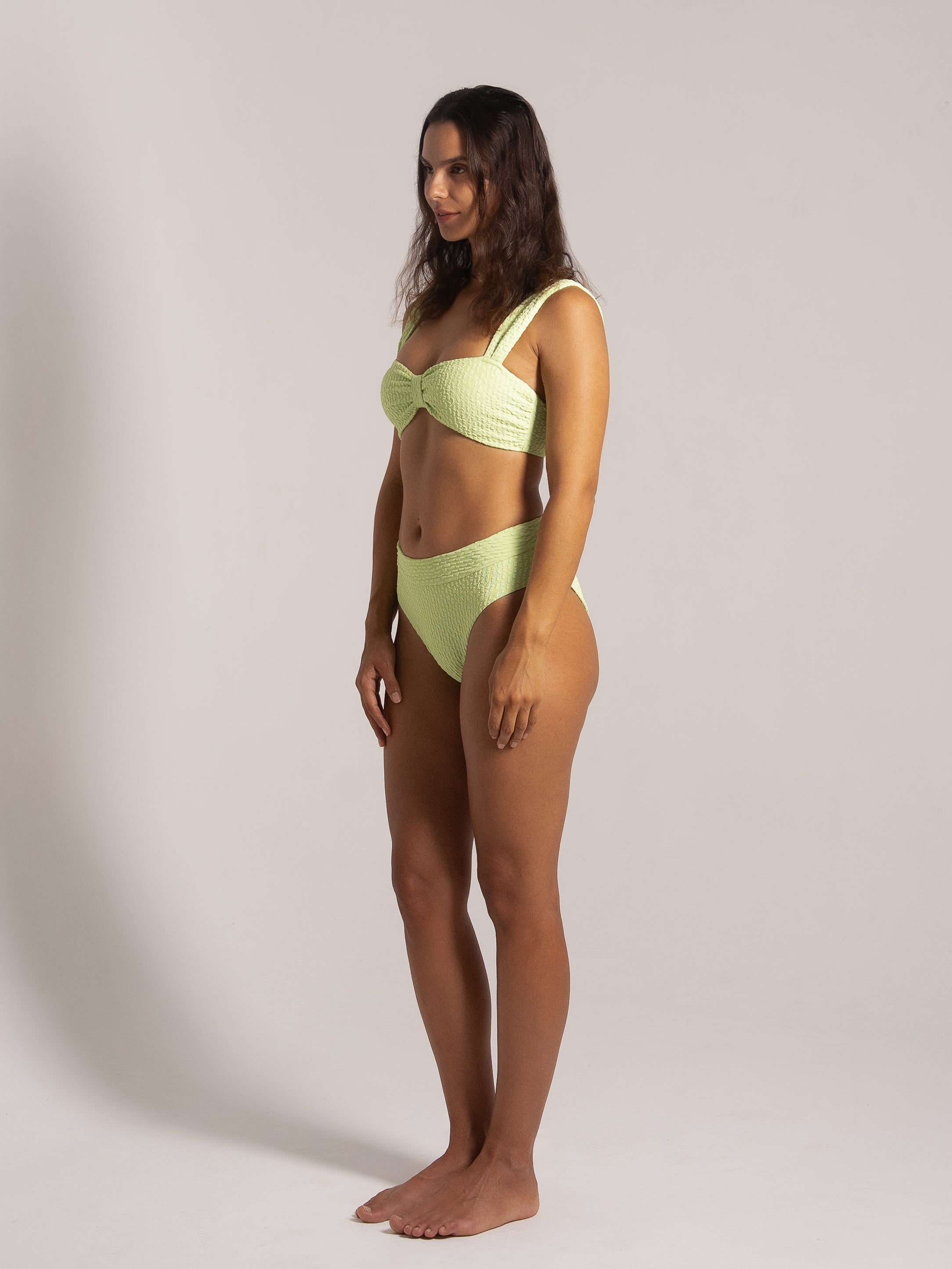 Side view of model in lime textured bikini set with structured top and full coverage bottom