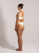Woman in mint green textured bikini with scoop back top and high-cut double-strap bottoms, back side angle view
