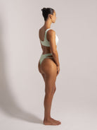 Side view of a woman wearing a mint green textured bikini with thick straps and high-waisted cut-out bottoms