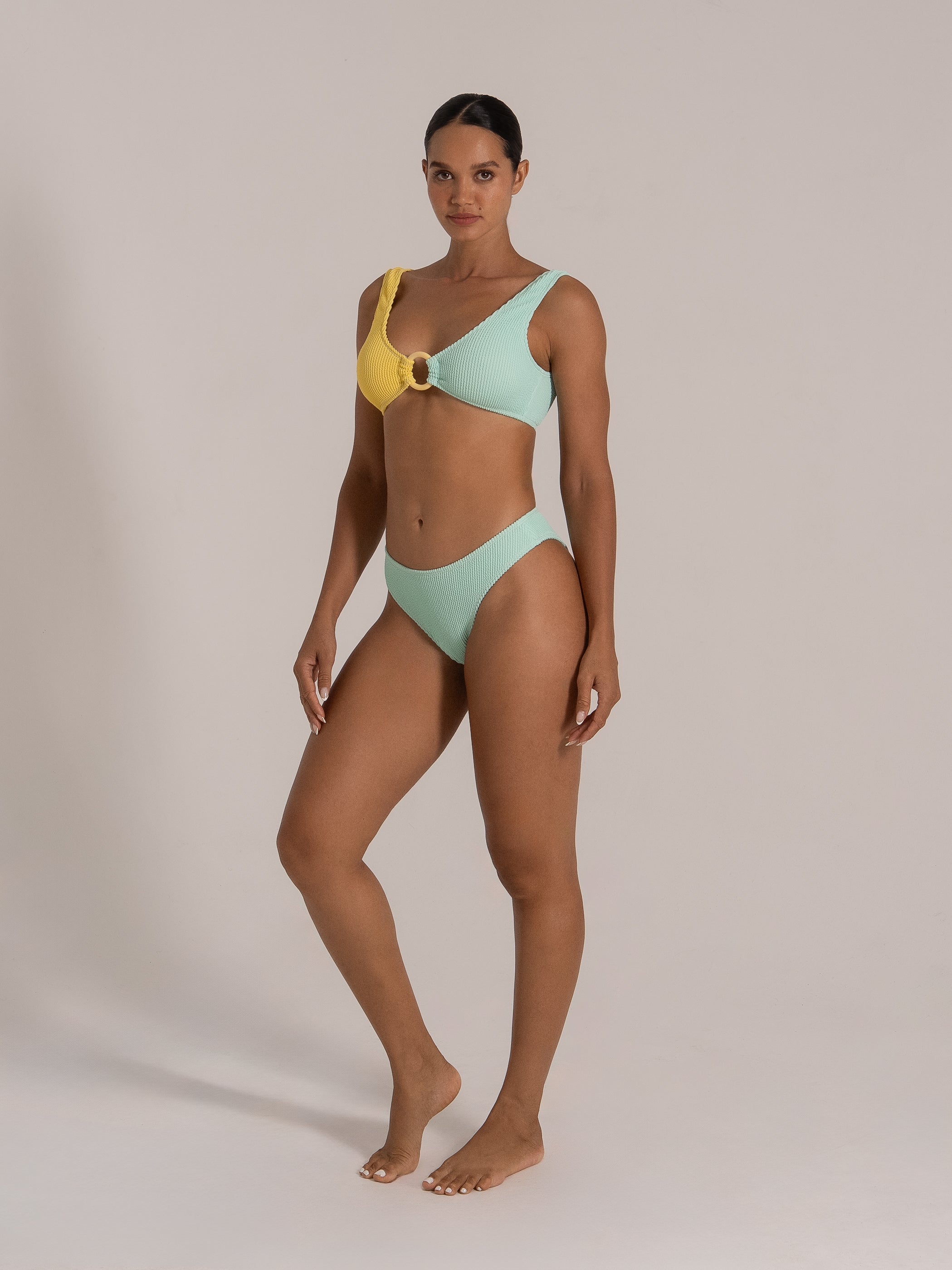 Side view of a model in a mint green crinkled bikini set featuring wide shoulder straps and secure back clasp.