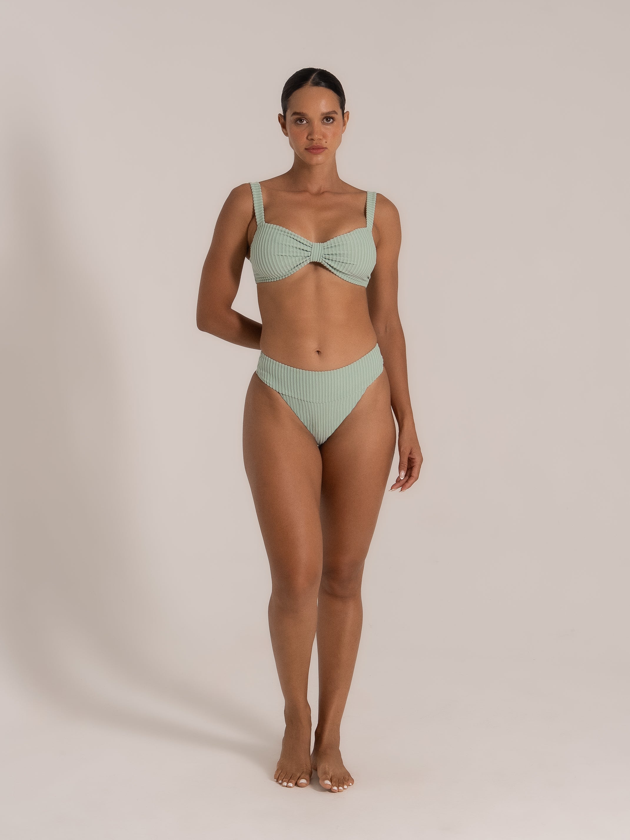 Model front-facing in a mint green bikini set with twist-front top and mid-rise bottoms.