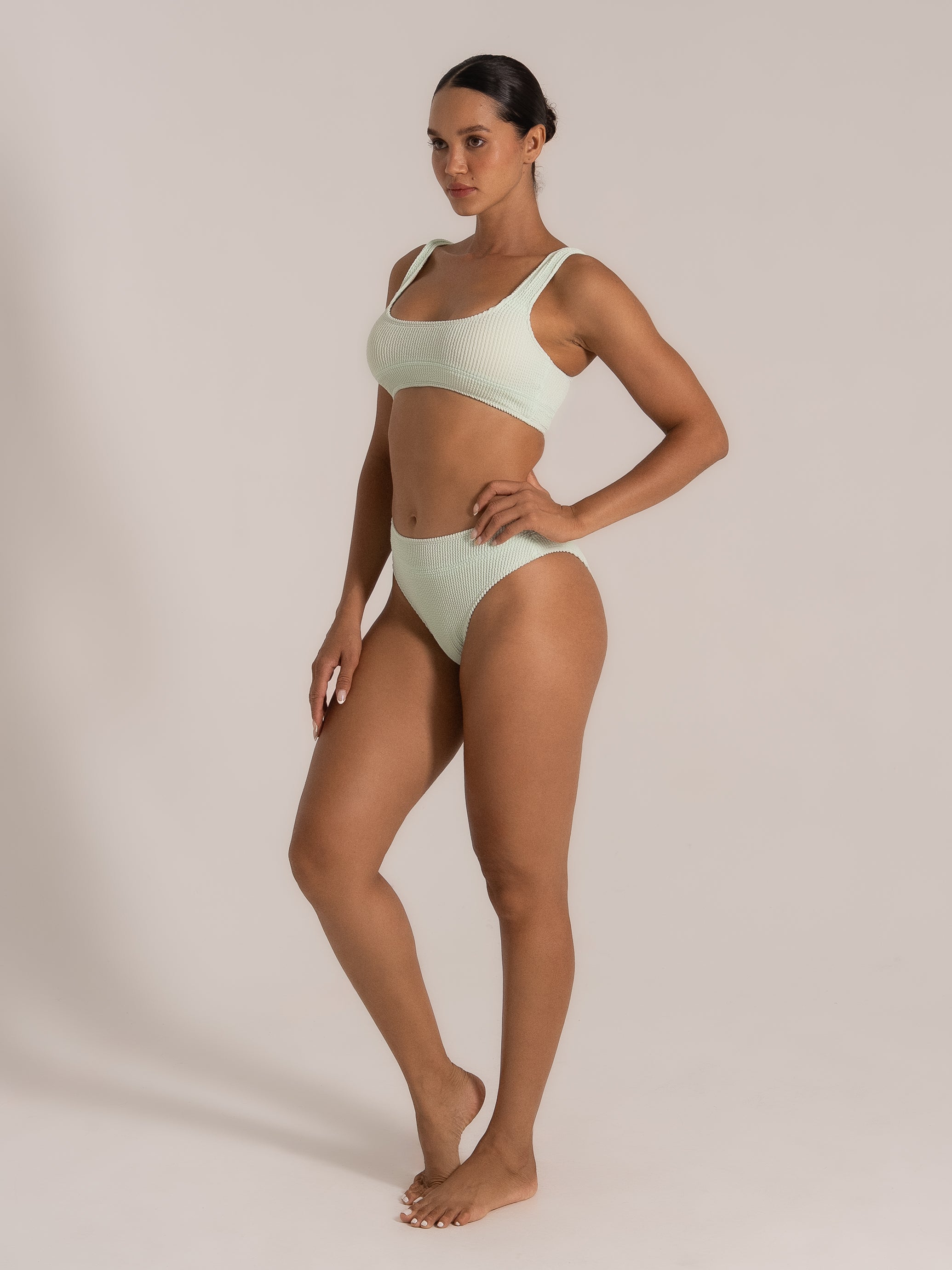 Side view of woman in mint green bikini set featuring wide shoulder straps and ribbed fabric