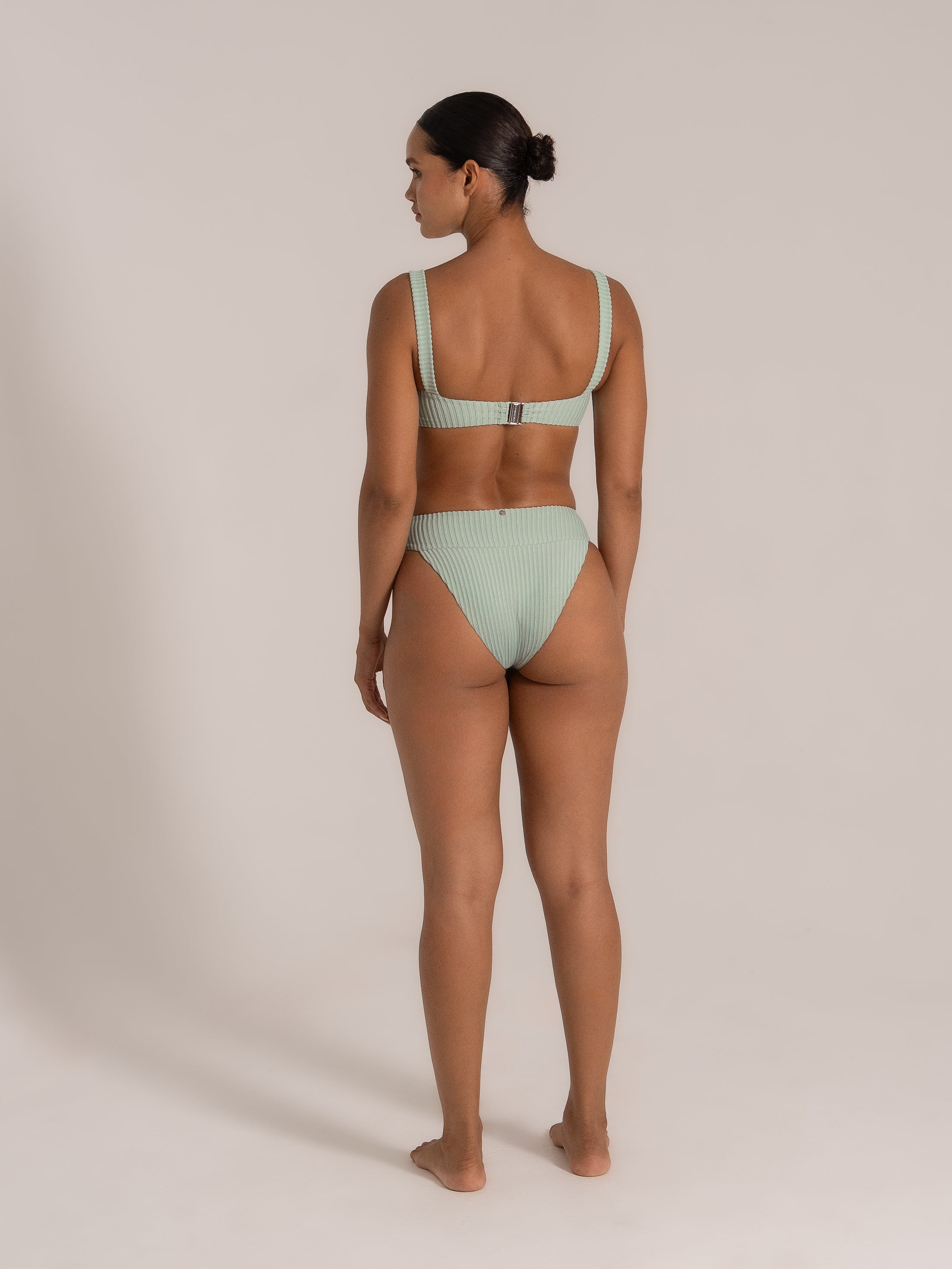 Model showing back view of mint green ribbed bikini set with wide shoulder straps and back clasp.