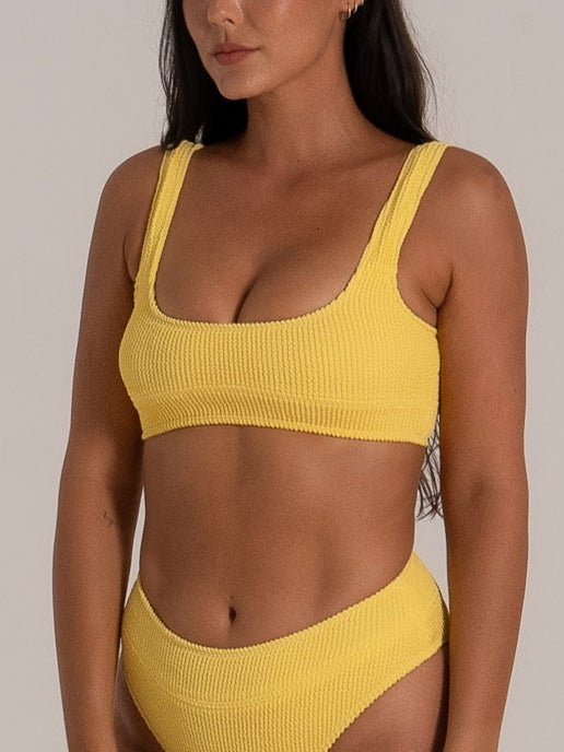Front angled view of model in mustard yellow bikini with ribbed texture and flattering high-leg bottom