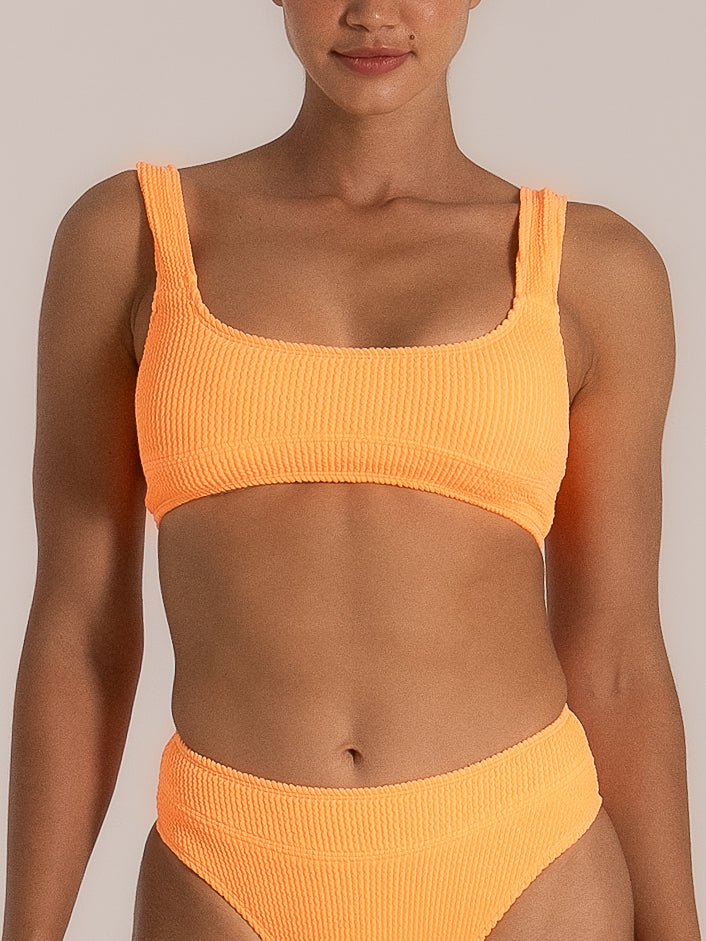 Front view of a woman wearing a neon orange bikini set with a square neckline top and high-waisted bottoms, made from a textured stretch fabric that adds a sporty and sculpting finish.