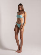 Model wearing aqua blue jacquard bikini angle standing by Ocean Mystery Swimwear - sustainable textured fabric