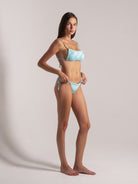 Model wearing aqua blue jacquard bikini angle view by Ocean Mystery Swimwear - sustainable textured fabric