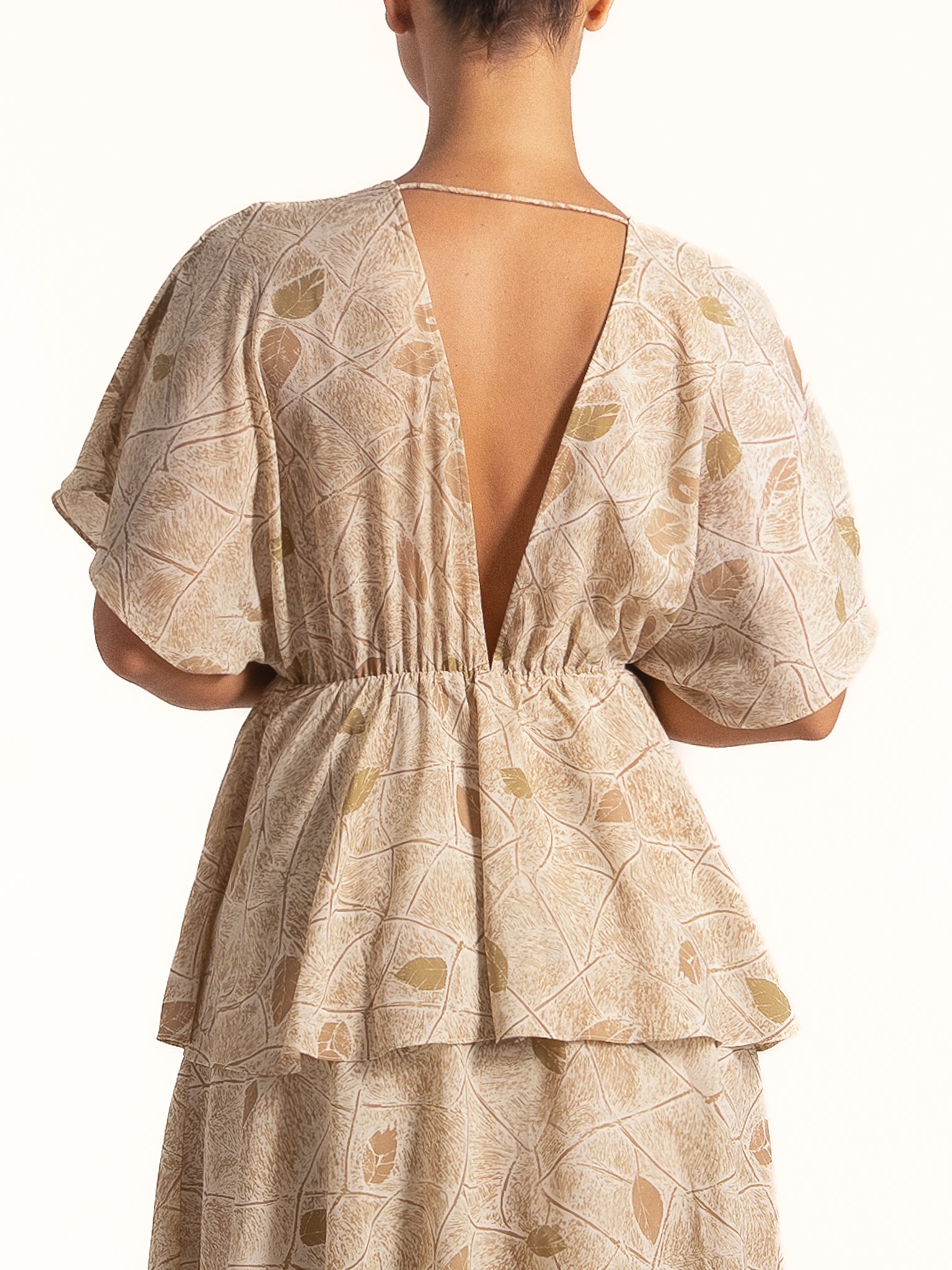 Back view of Ocean Mystery beige floral tiered maxi dress with open back and elastic waist design.