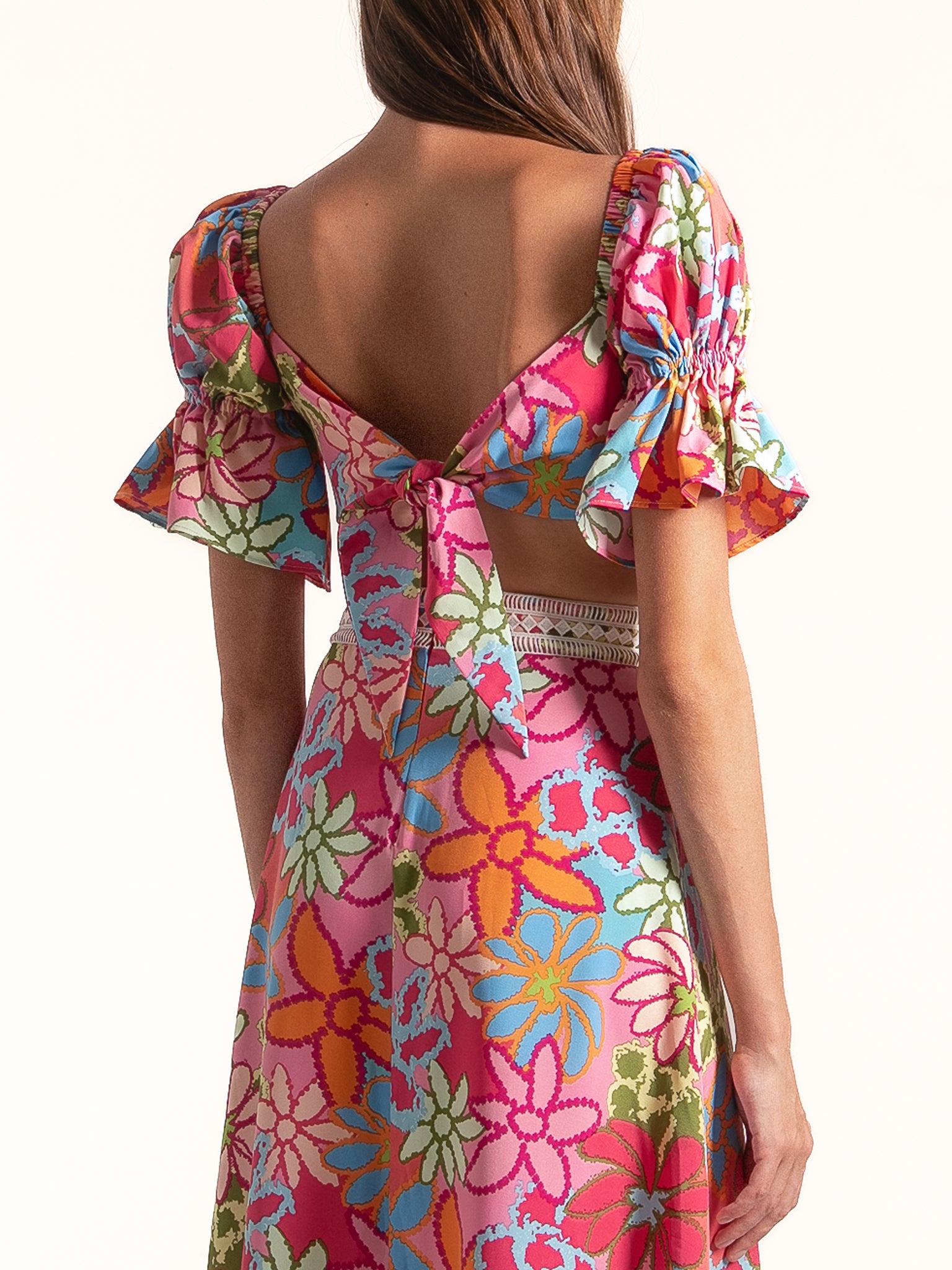 Back view of Ocean Mystery pink floral puff sleeve midi dress with open back and tie detail.