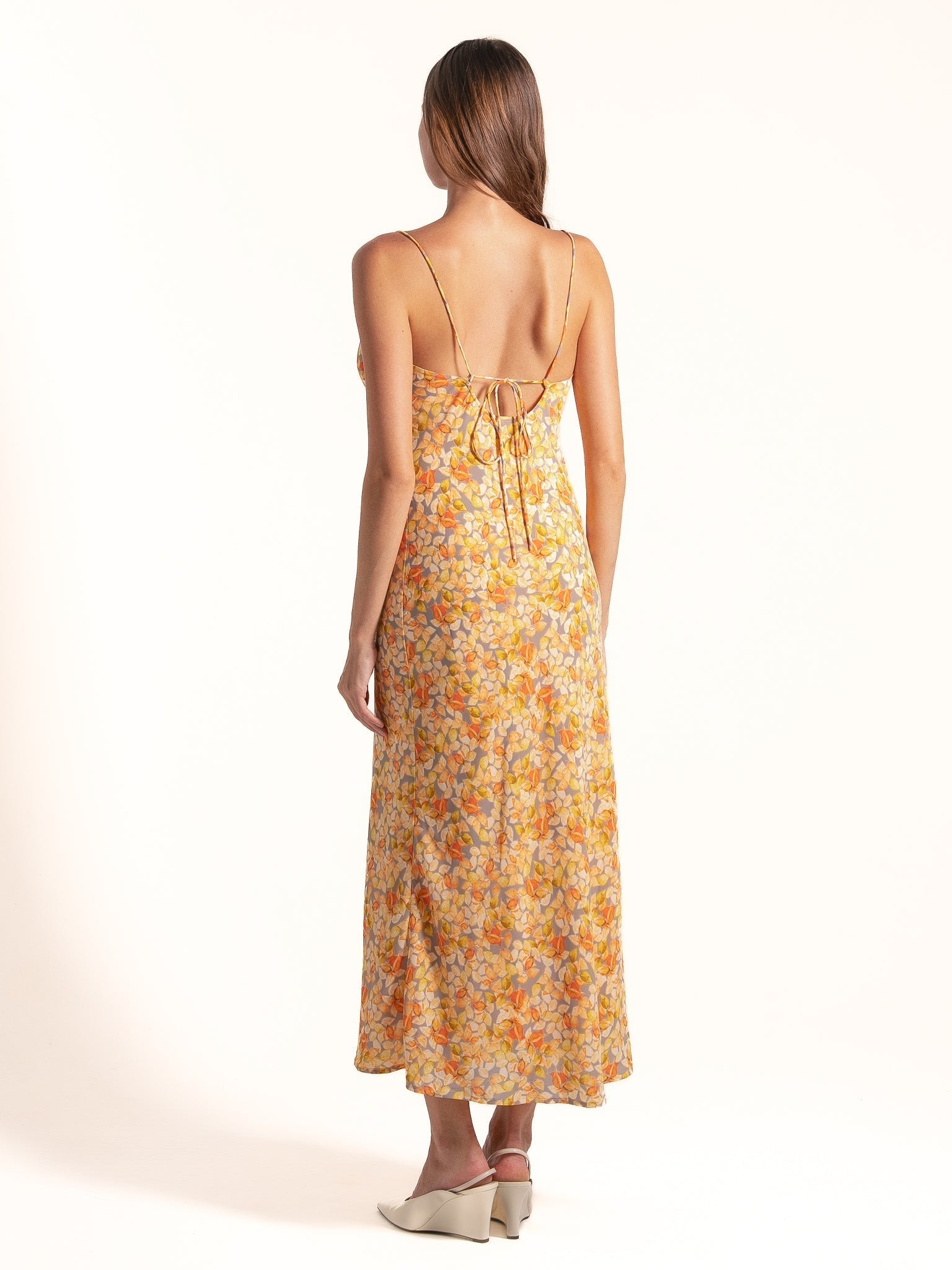 Model wearing Ocean Mystery yellow floral slip midi dress with cowl neckline and lightweight fabric.