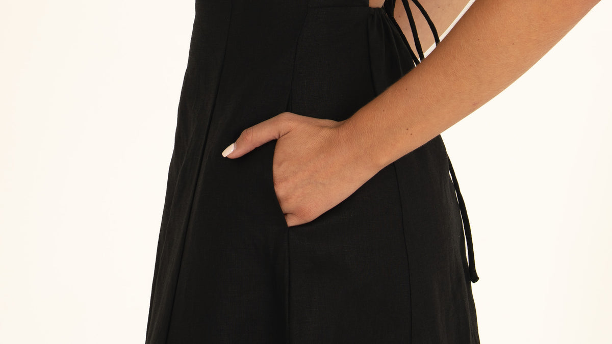 Close-up detail of the 100% pure Onyx linen texture and the discreet side pocket opening on the midi dress.