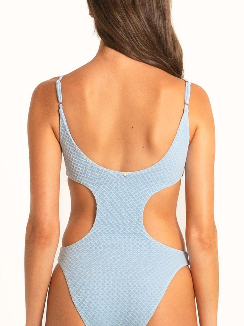 Rear shot of model in light blue cut-out swimsuit showing scooped open back and cheeky fit