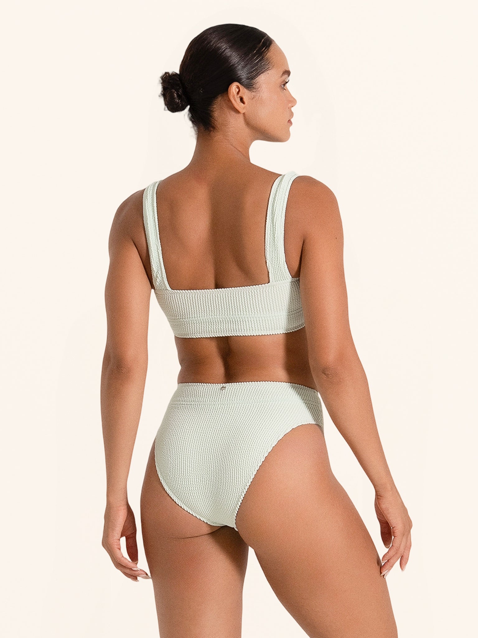 Pastel green swimsuit top designed with square neckline and wide straps.