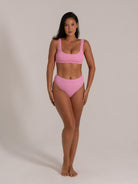 Front view of model in pink textured high waisted bikini bottom and square neckline top