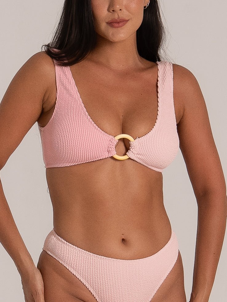 Close-up front view of a pink textured bikini featuring a statement ring detail and scoop neckline.