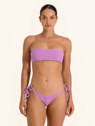 Front view of woman wearing purple strapless bandeau bikini top with textured design.