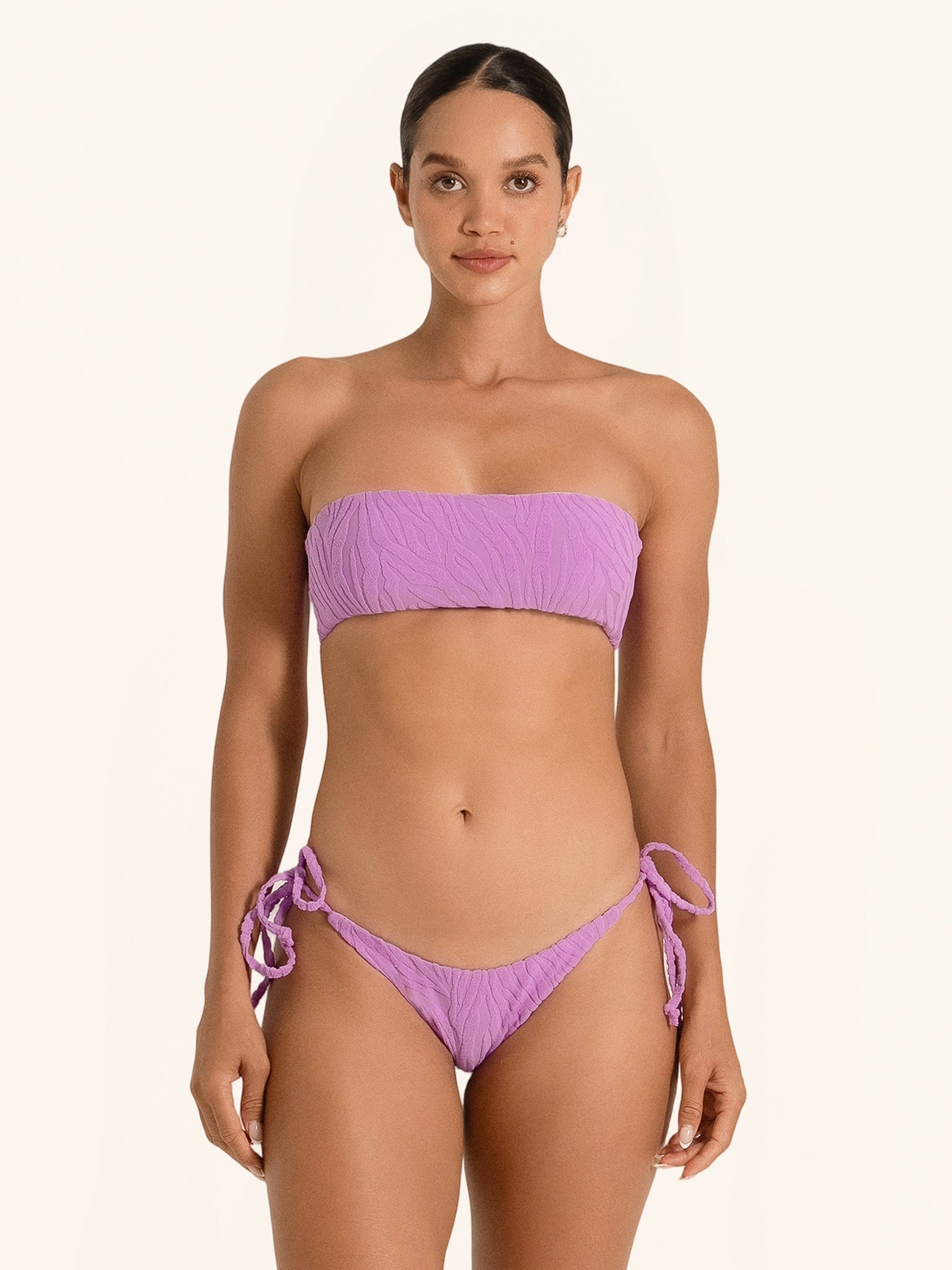 Front view of woman wearing purple strapless bandeau bikini top with textured design.