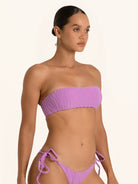 Side pose of purple bandeau bikini top showing strapless ruched detail.