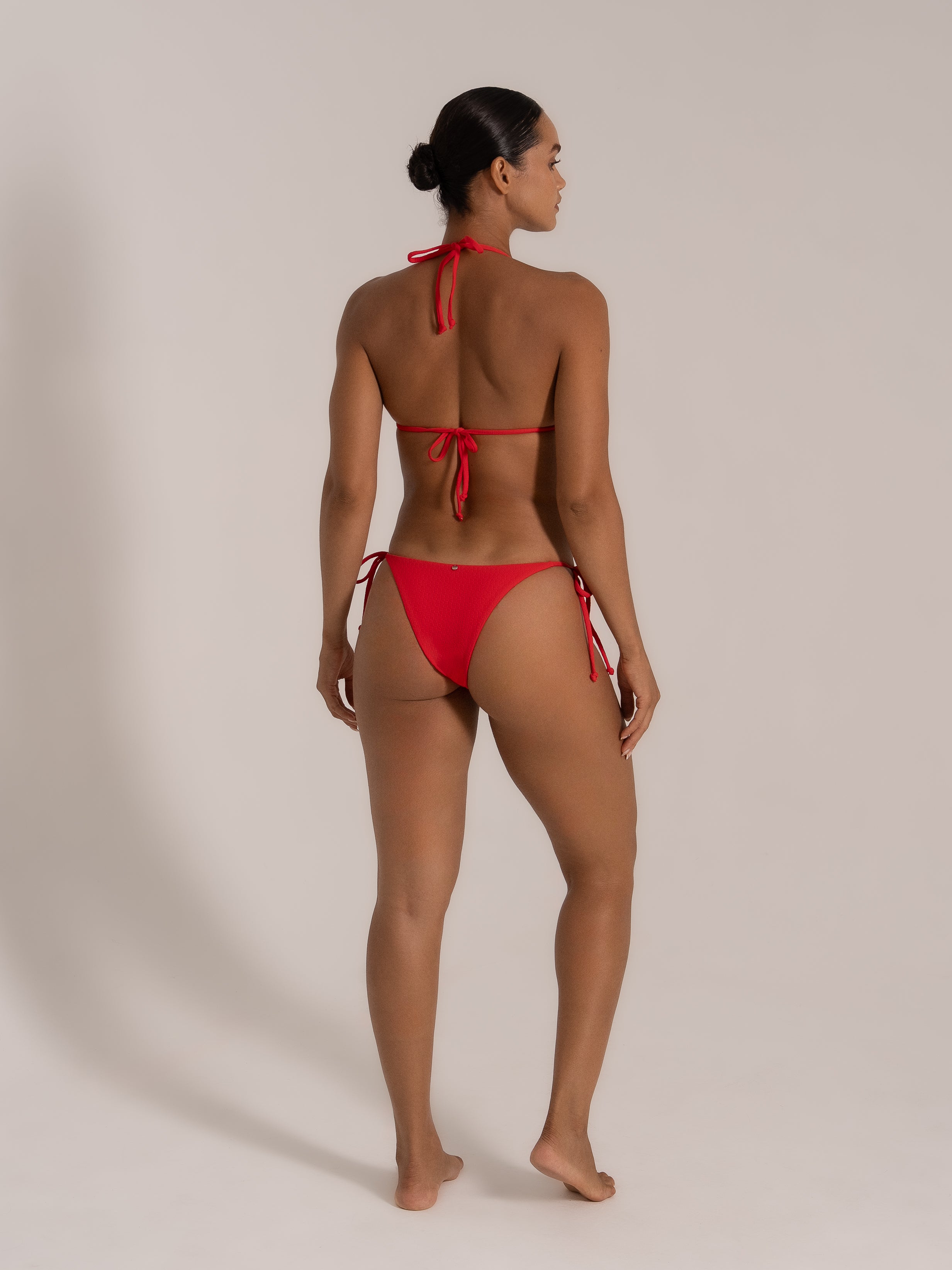 Back view of model in red halter bikini with tie-up back and cheeky bottoms